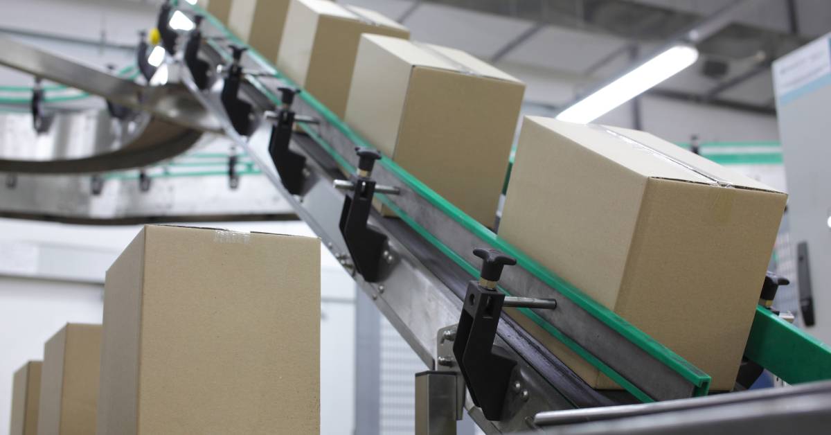 Rows of cardboard boxes moving on a conveyor belt inside a manufacturing plant filled ready for shipping
