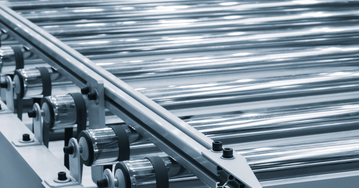 A conveyor belt with a series of metal rollers in an industrial setting featuring a close-up view of the machinery.