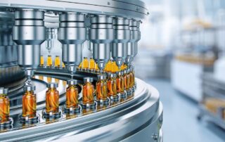 A conveyor system in a pharmaceutical manufacturing facility carrying numerous orange vials with silver caps.