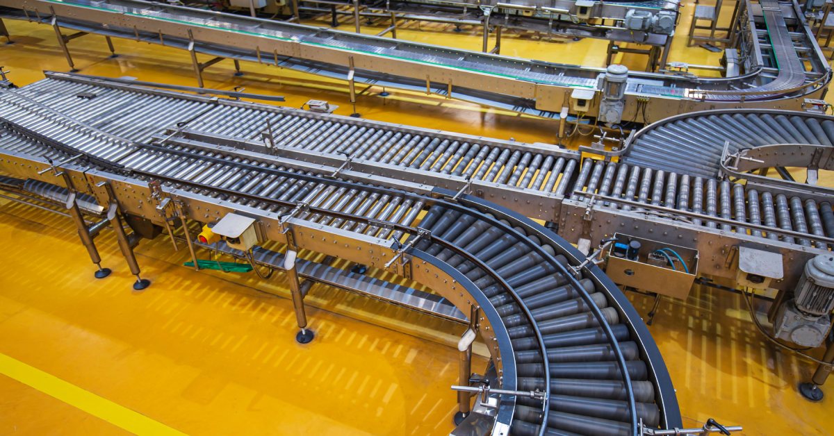 A conveyor belt with a roller crossing over it, representing the intersection of two paths in a production line.