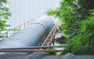A covered conveyor system connects to a facility wall. The system features a curved cover made of metal.